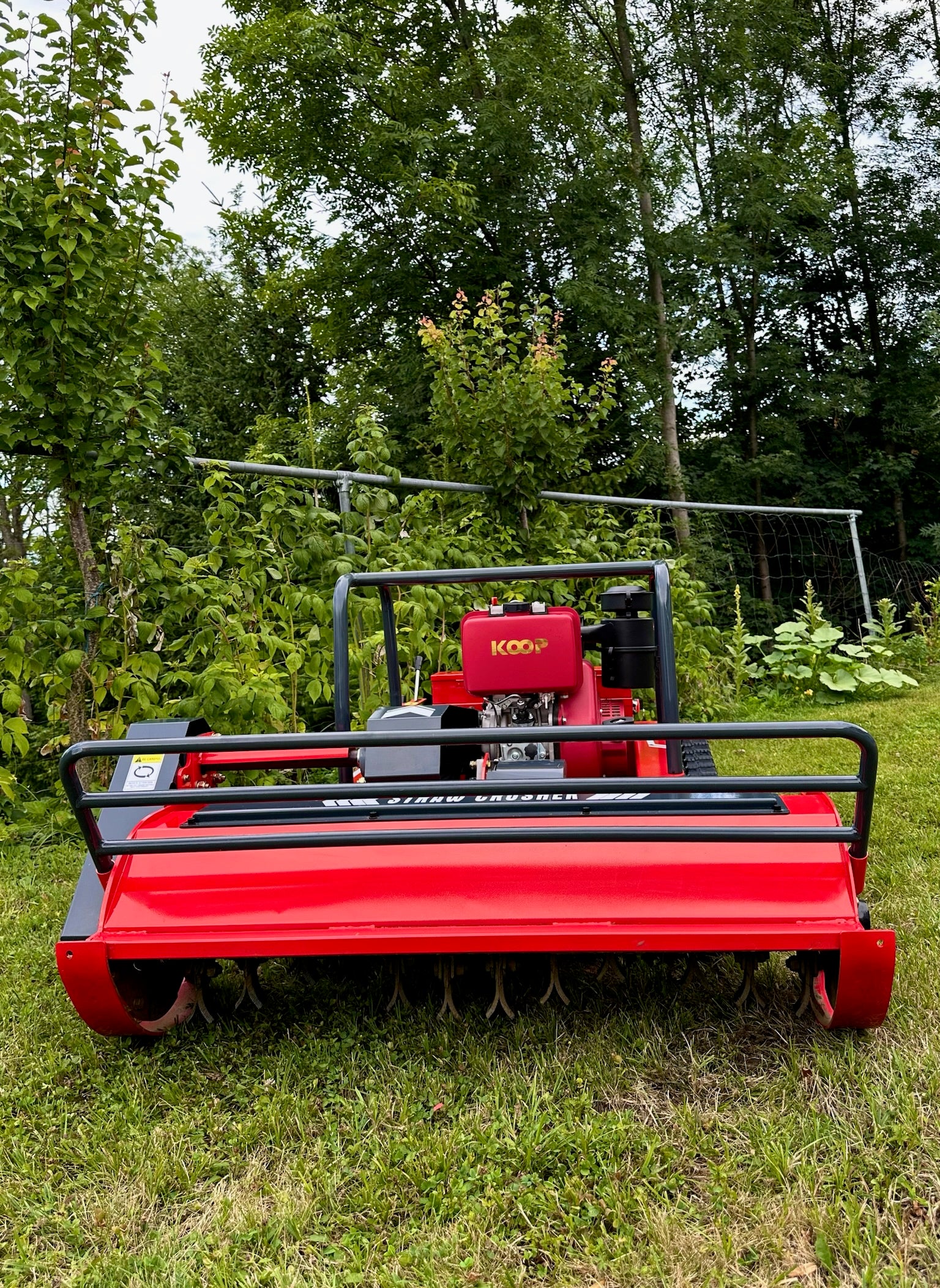 Leistungsstarker Mulcher auf Rasenfläche, rote Maschine, Maschinentechnik für Gartenarbeit